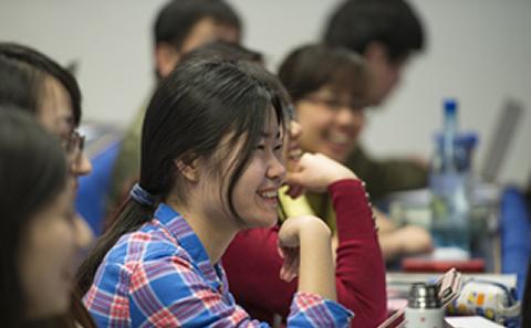 Student sat smiling in course lecture