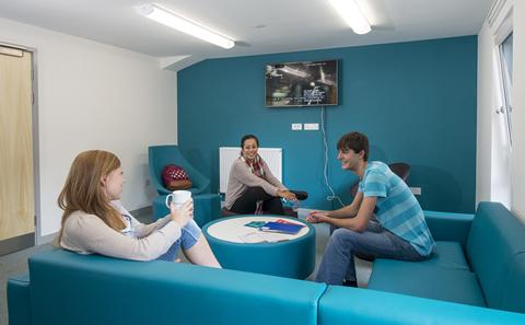 Three students sat inside student accommodation.