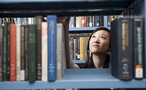 A student taking a book from a shelf.