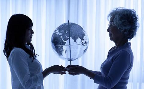 Two woman holding up a globe of the world