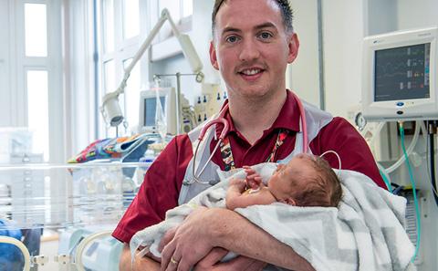 Colm Darby holding a newborn baby.