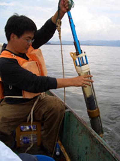 Researcher Enlou Zhang examines at a core sample lifted from the bed of the lake