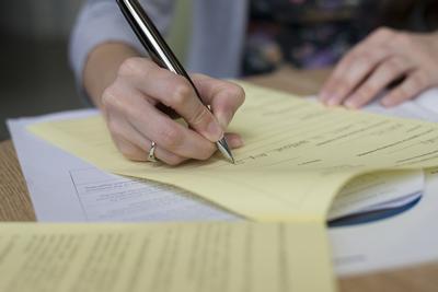 Person writing on yellow paper