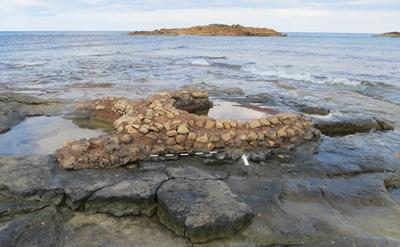 Es sind zu sehen die archäologische Überreste von römischen Fischverarbeitungsbottichen. Der Fundplatz liegt bei Kainopoli in Libyen. Der Fundplatz ist in die Datenbank aufgenommen worden. 