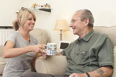 Woman giving cup of tea to man