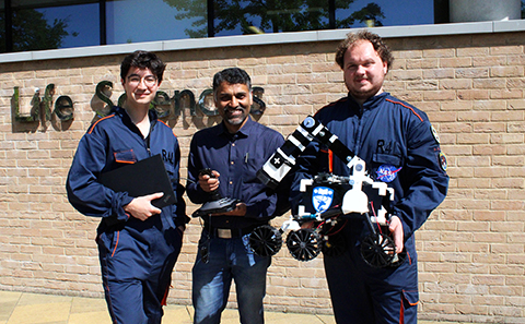 Three men holding a rover robot