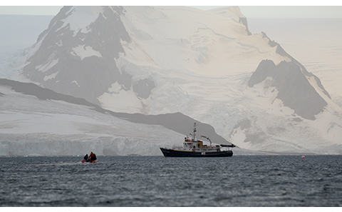 Small boat approaches larger vessel in Antarctica.