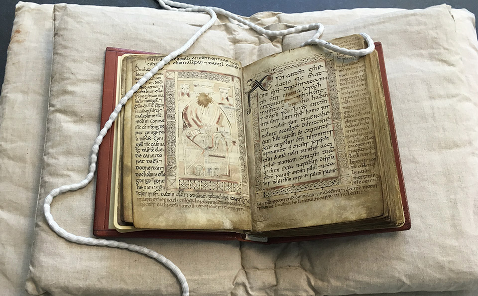 Ancient Gospel book with pages open on museum stand