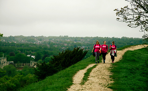 Three women walking in green, hilly countryside
