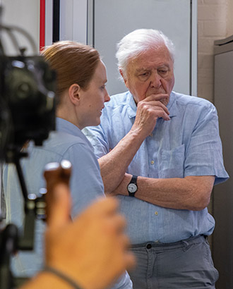 Woman speaking to Sir David Attenborough in lab