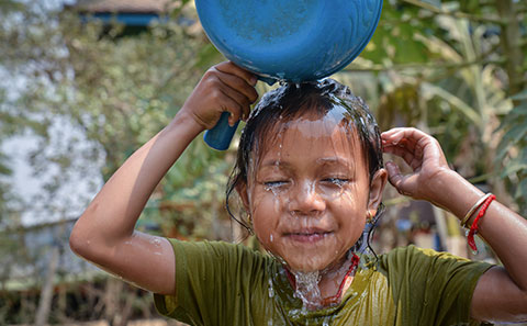 Young boy pours water over head