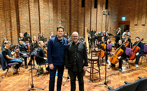 Two men standing in front of orchestra