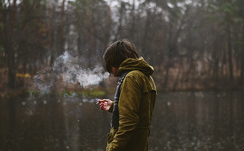 Teenage boy smoking in woods