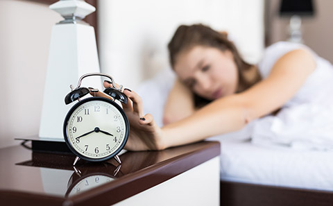 Woman in bed turns off alarm clock