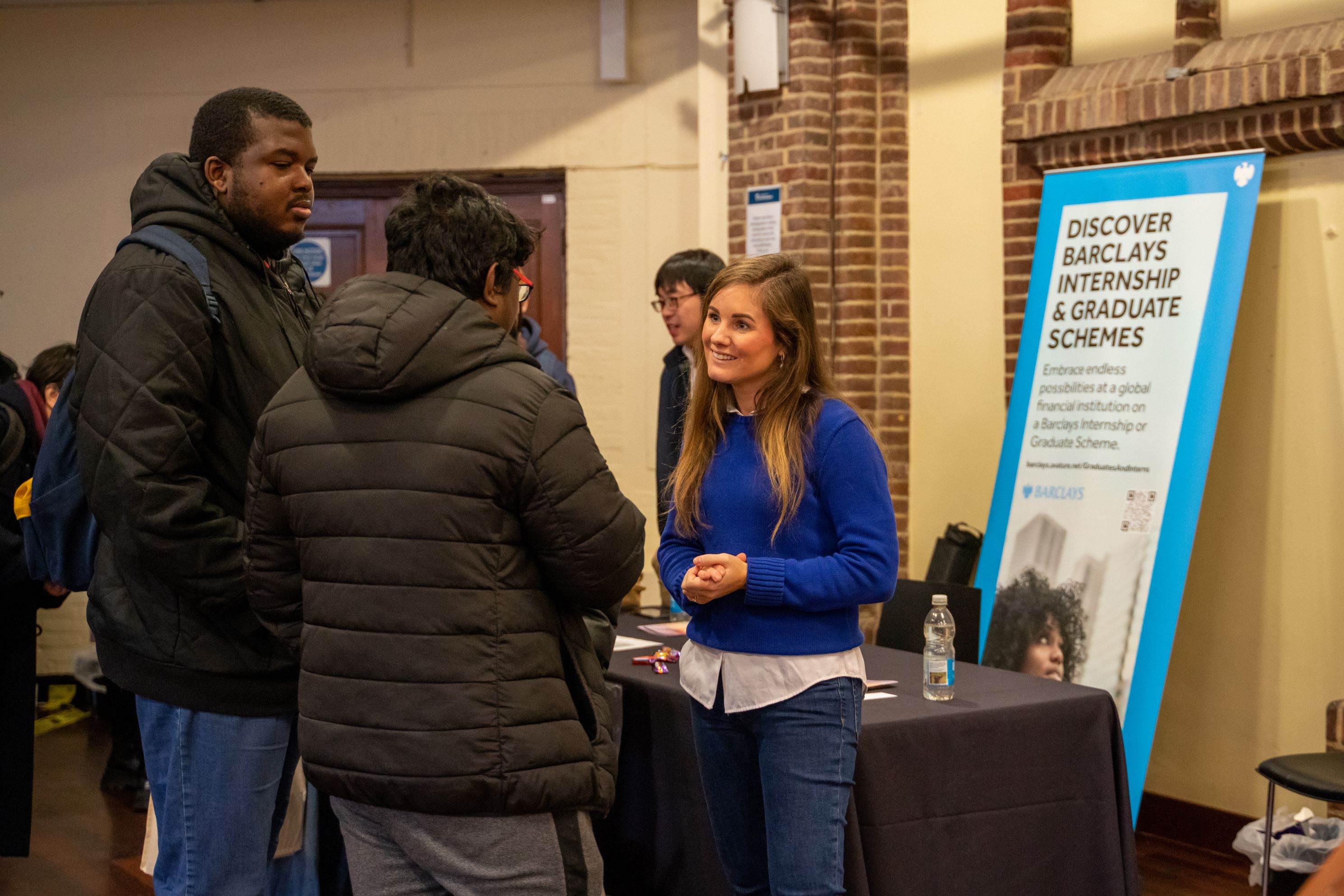 2 students in conversation with an advisor at a graduate event