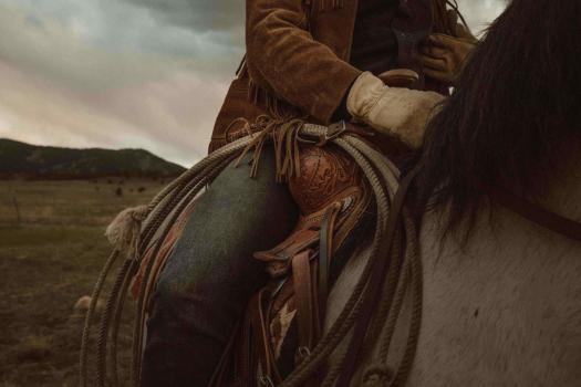 Close up of a cowboy's knee on a horse