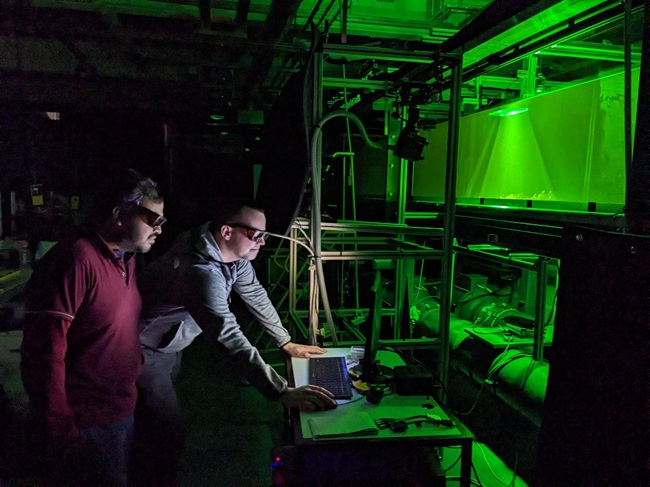 Researchers operating laser-based flow measurement equipment at a recirculating water tunnel facility