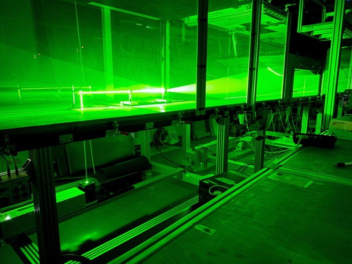 Particle image velocimetry (PIV) equipment using a green laser to measure airflow in a wind tunnel experiment.