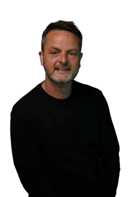 Paul Mackie is wearing a black jumper and facing the camera