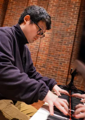 Jiahao Wang playing a grand piano in the Turner Sims hall.