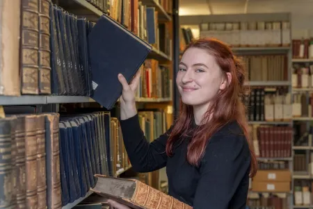 Joely Fake, putting a book back onto the shelf in the library