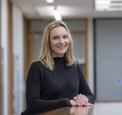 Health Psychology masters student, Lauren is leaning on a table and smiling at the camera