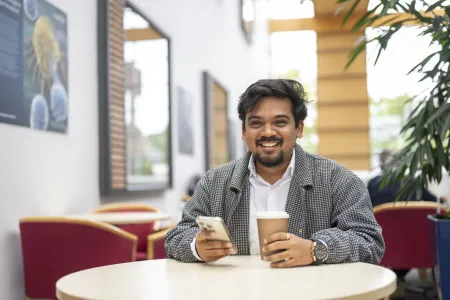 Shubham Barnwal sitting at a table and drinking coffee