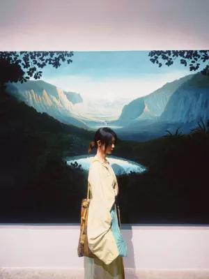 Jinghan is stood in front of a painting of a valley