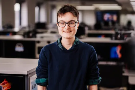 Portrait image of Lucy standing in a lab, smiling at the camera.