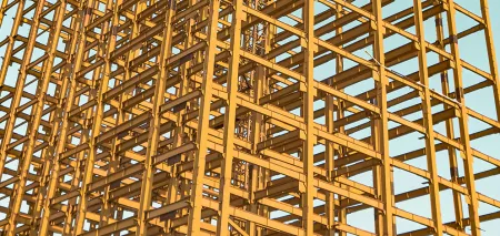 Close up of the construction of a building's yellow iron framework. At first glance it looks like an abstract set of geometric shapes.
