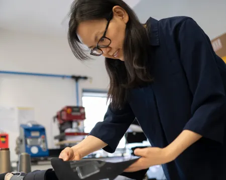 Professor Kai Yang examining a textile prototype in an e-textiles research workshop.