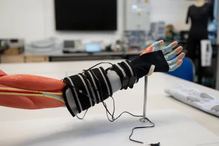 Wearable textile prototype fitted to a model arm with sensors and wiring for healthcare research.