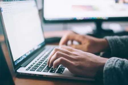 A stock image of hands using a laptop keyboard.
