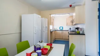 Empty modern communal kitchen with the table set with breakfast cutlery.