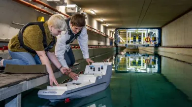 Two students test a model boat in the towing tank