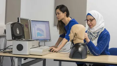 2 students conducting a hearing test on a dummy.