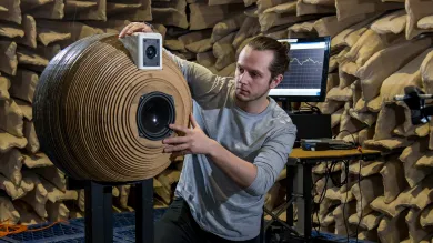 A student positioning a novel, spherically-designed speaker system inside the large anechoic chamber for testing.