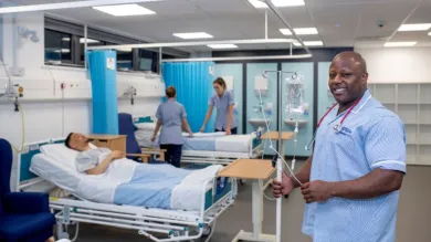 Nursing students working on a simulated ward with beds and drip