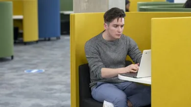 A student quietly studies using a laptop in a study pod in the centenary building