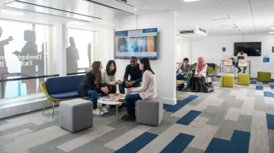 A small group of students sit and chat in a corner of the Business School study space.