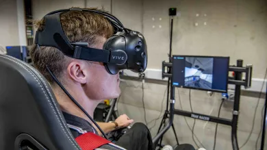A student wears virtual reality goggles in the flight simulator
