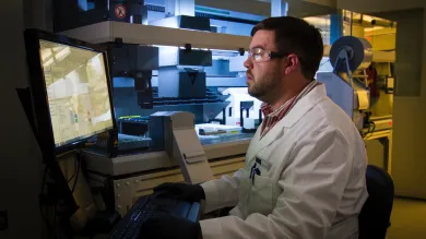 A man in lab sitting in fromt of a computer.
