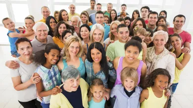 A stock photo of a large group of people of all ages, genders and ethnicities smiling up at the camera.