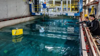 A student uses the 138m towing tank to investigates a buoy's hydrodynamic performance while a researcher offers advice