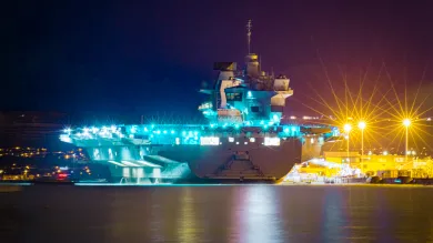 Aircraft carrier lit up at night in dock