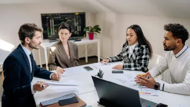 Group of 4 people talking around a work table