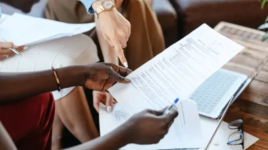 Pexels image showing hands holding a sheet of paper and pen, in a formal meeting