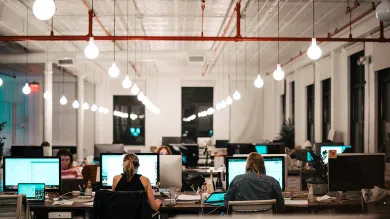 Unsplash image of seated workers using computers, in a modern office with high ceilings