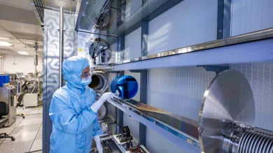 A researcher in a cleanroom suit examines wafers in Low Pressure Chemical Vapour Deposition (LPCVD) horizontal furnace