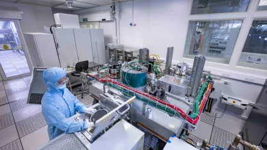 A researcher in cleanroom suit uses the Buhler Helios Batch Sputter Tool in the nanofabrication cleanroom